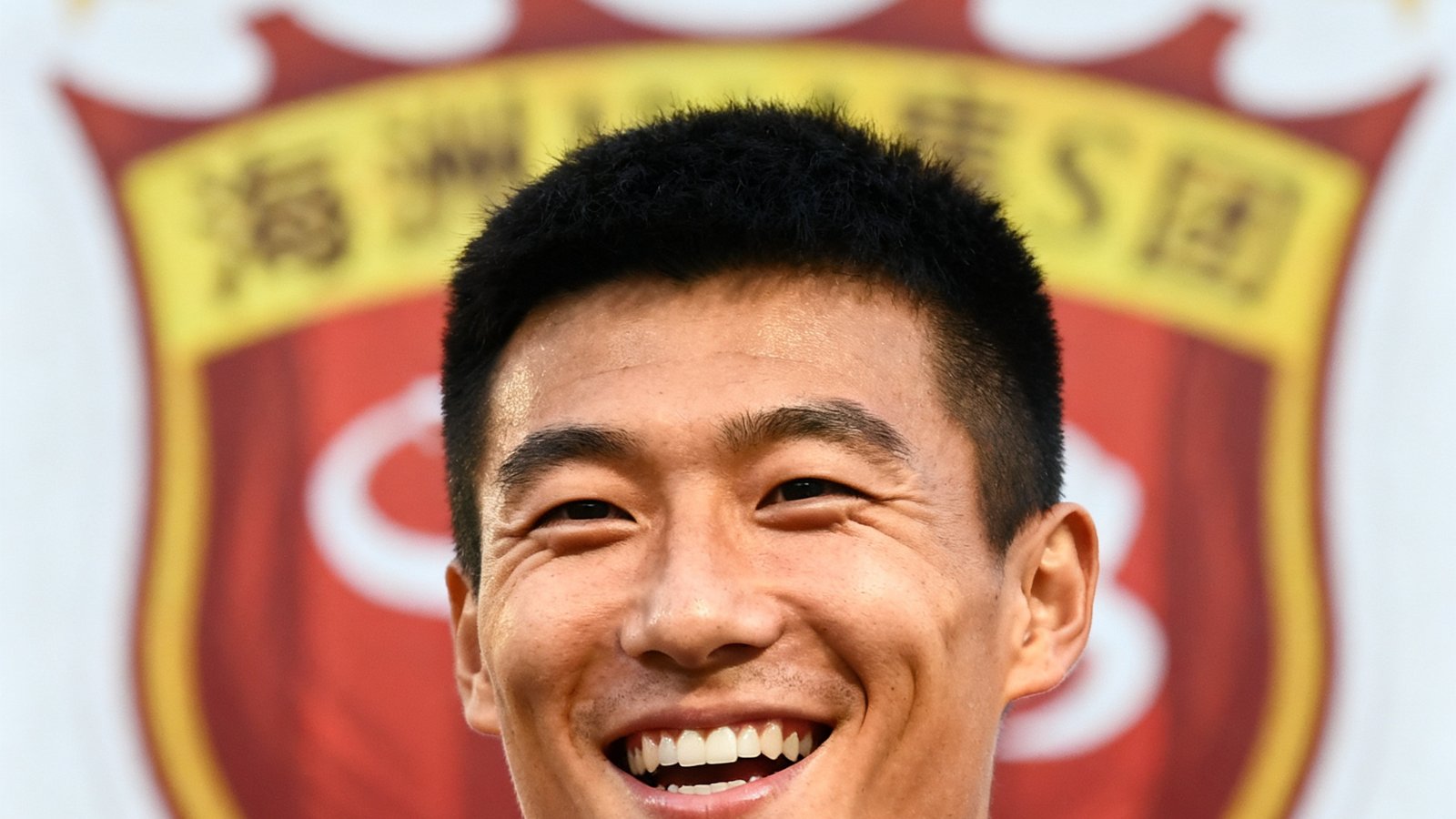 武磊赛后接受采访，面带笑容，背后是海港队徽